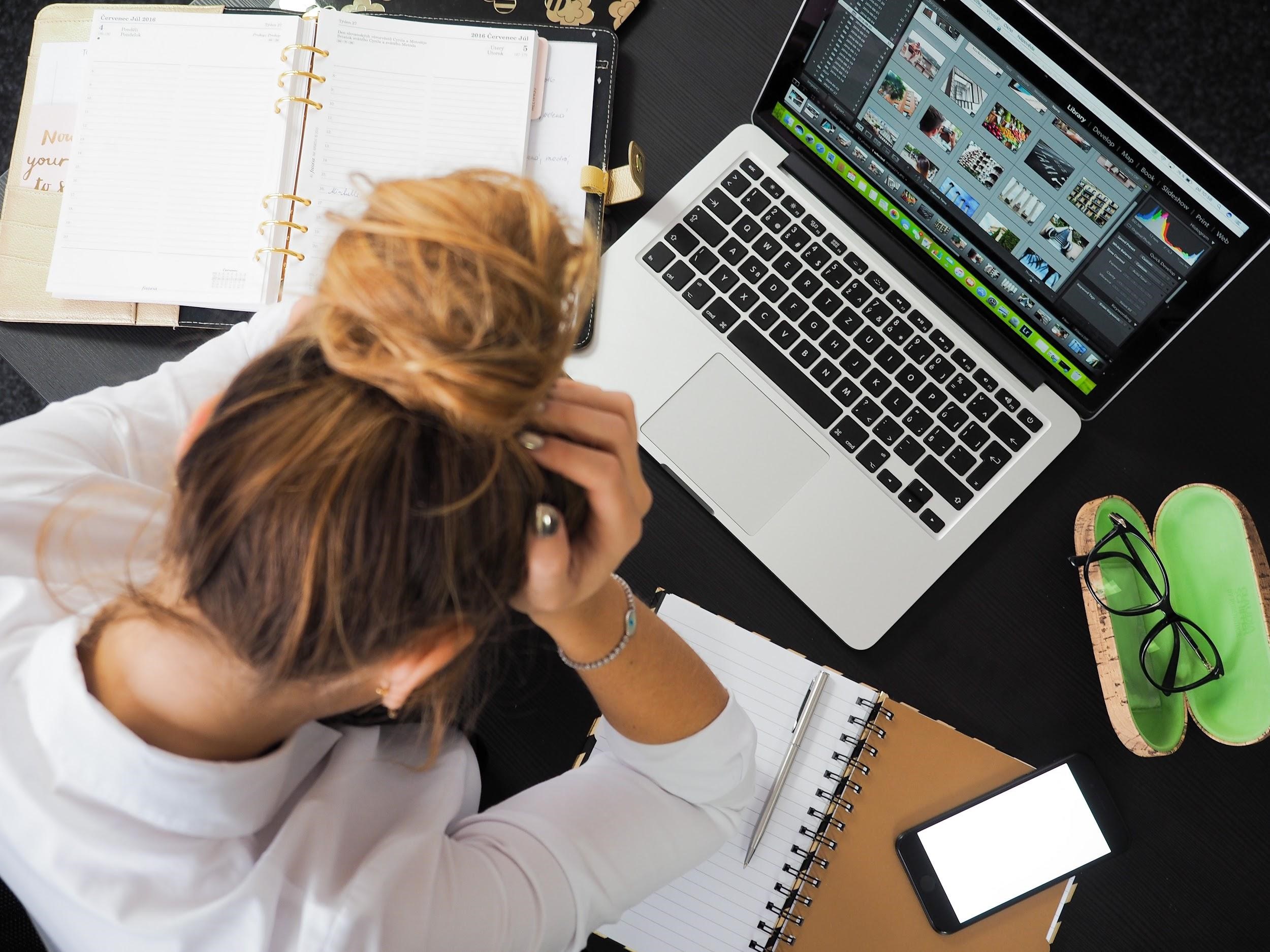 Frustrated blond businesswoman at the desk in an office with a laptop and diary